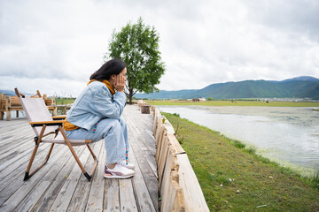 Fototapeta premium Travel woman sitting in chair looking at amazing mountains and lake view, wanderlust travel and people with landscape concept.