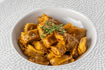 Agnolotti del Plin seasoned with roast sauce, stuffed egg pasta ravioli from the tradition of Piedmont, Italy. Plin in white plate