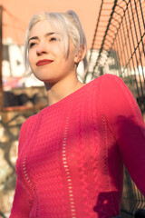 Fototapeta premium Smiling young woman by a gate in urban setting