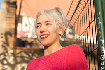 Smiling young woman by a gate in urban setting