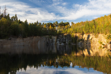 Granite quarry Rasna with reflection and trees at day. Czech travel destination landscape