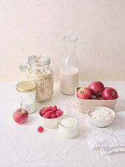 Ingredients for making overnight oats or a porridge bowl. Grains, fruits, berries and dairy products. White background