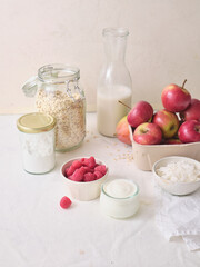 Ingredients for making overnight oats or a porridge bowl. Grains, fruits, berries and dairy products. White background