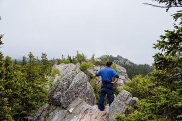 Naklejka premium A Hiker Enjoys the View Overlooking Majestic Misty Mountain Peaks in a Beautiful and Serene Natural Landscape Surrounded by Nature