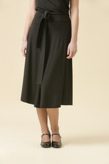Female model wearing simple timeless black midi skirt. Fashion studio shot.	