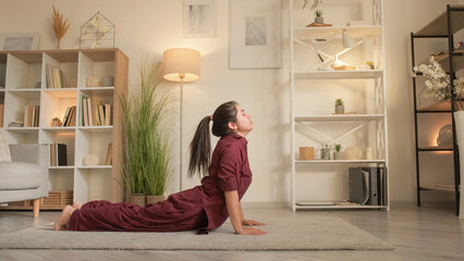 Yoga training. Home gym. Healthy hobby. Calm flexible woman practicing bhujangasana cobra pose...