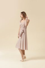 Fototapeta premium Female model wearing monochrome pale pink outfit. Classic sleeveless blouse and wide midi skirt. Fashion studio shot.