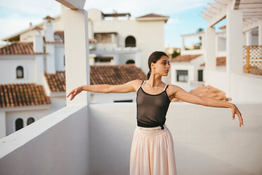 An Elegant Dancer Gracefully Posing on a Rooftop with a Beautiful Scenic Background - Powered by Adobe