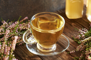 Herbal tea in a glass cup with fresh heather or Calluna vulgaris flowers harvested in the forest