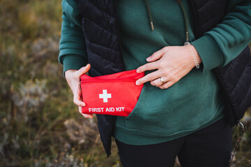 A person is gripping a first aid kit tightly in their hands, implying that they might be equipped...