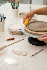 Using sponge for pottery class. Absorbing sponge to get rid of excess moisture. Applying more moisture on clay products. Smoothing clay with a sponge. Ceramics workshop.