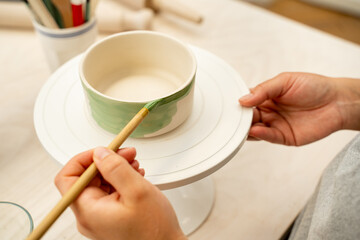 Girl is making a colorful decoration of a clay project with paint and water. Painting ceramic...