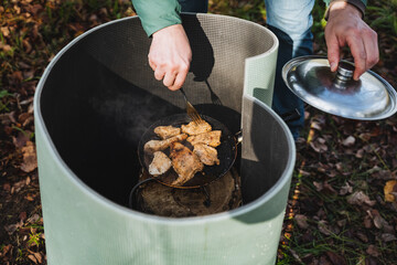 An individual is preparing a meal by creatively using a trash can as an unusual cooking vessel, showcasing a truly unique and innovative approach to food preparation that challenges norms