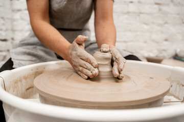 Girl is making a bowl on a pottery wheel with your own hands. Forming the proper size and shape of pottery with increasing speed of a pottery wheel.
