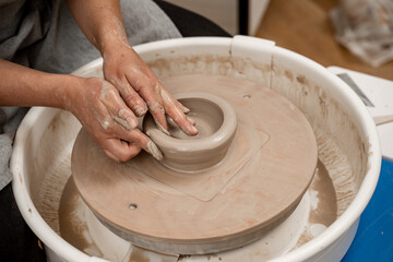 Wheel throwing. Learning how to model clay into different shapes with pottery wheel. Creating a ceramic bowl by yourself in a pottery class.