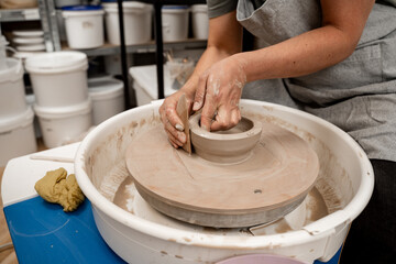 Making smooth edges of pottery with a wooden scraper and a pottery wheel. Cutting the lines on sides of a clay product with a wooden scraper.