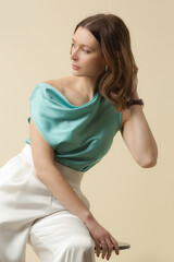 Female model wearing silk outfit, mint sleeveless top and white trousers. Classic and simple...