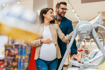 Attractive middle age couple enjoying in buying baby cradle swing. Beautiful couple in a baby shop or store. Child expecting concept.