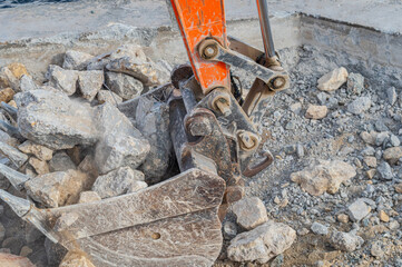 Excavator bucket filled with stones and pieces of concrete