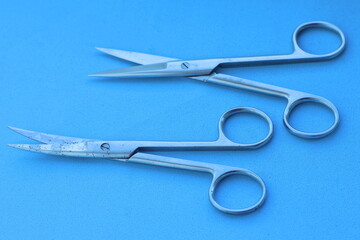  two sterile surgical sharp iron open industrial  for removing sutures scissors lie on blue table in operating room in hospital
