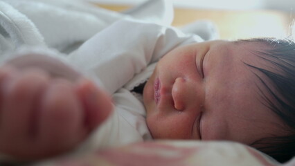Newborn baby grimacing in sleep, close-up of face showing discomfort, likely passing gas, capturing the natural and candid moments of early life