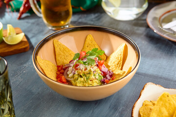 Delicious Guacamole with Tortilla Chips in Ceramic Bowl on Table – Mexican Cuisine