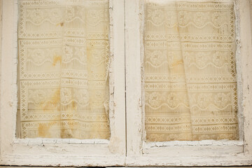 The texture of an old wooden window with curtains. White painted window frame