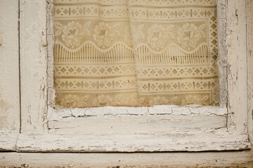 The texture of an old wooden window with curtains. White painted window frame
