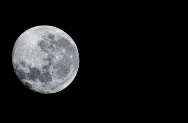the image shows a full moon in a dark night sky. The moon is bright and detailed, with a rough and uneven surface. The sky around the moon is completely black, which highlights the moon's beauty.