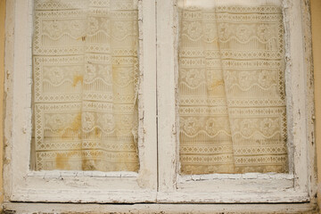 The texture of an old wooden window with curtains. White painted window frame
