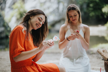 Two women having a peaceful outdoor picnic together, bonding over painting and craft activities in a natural setting.