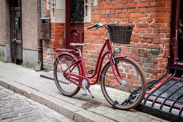 Red bicycle with a wicker basket, stylish city transportation by red brick wall