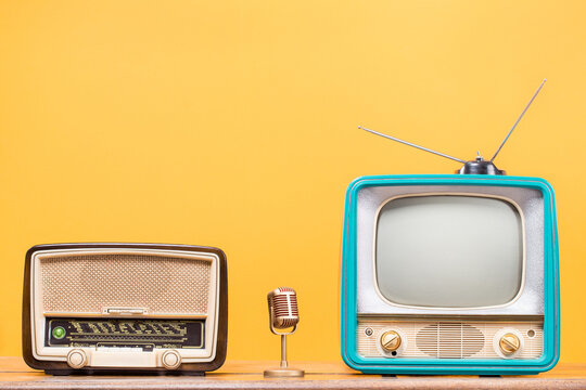 Retro radio, old TV and golden microphone front yellow background. Vintage style filtered photo