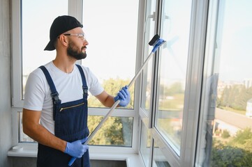 Cheerful male person cleaning window