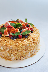 A stunning Napoleon cake adorned with fresh figs, raspberries, blueberries, and sprigs of mint. 