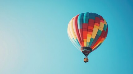 Naklejka premium Colorful hot air balloon soaring in a clear blue sky creating a vibrant spectacle in the atmosphere