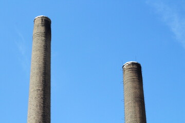 Two Big chimneys in factory against blue sky background
