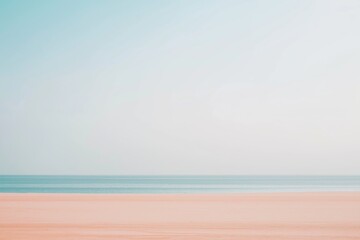 A tranquil scene of a sandy beach with the calm ocean extending to the horizon and a clear sky above.