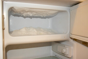 An interior view of a freezer showing ice buildup and frost accumulation. A reminder for regular maintenance and defrosting to keep appliances efficient and clean.