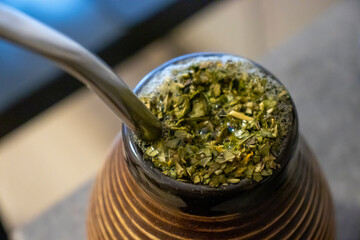 Close-up of a traditional yerba mate cup filled with dried leaves and a metal straw. Enjoy the cultural experience of drinking mate. Perfect for lifestyle and beverage photography.