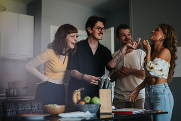 A joyful group of friends laughing and enjoying a light moment in a stylish kitchen setting,...