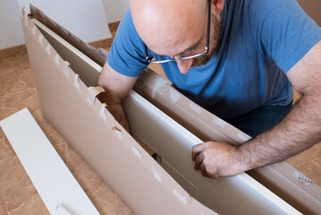 The man assembling new furniture in his house