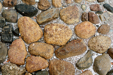 Stone background, old historic cobble stone road, background with multicolored stones on the road, closeup