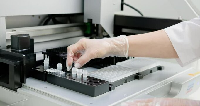 Laboratory technician wearing gloves placing microplate into automated machine for scientific analysis. Modern laboratory setup for accurate research and development. Scientist Placing Microplate.