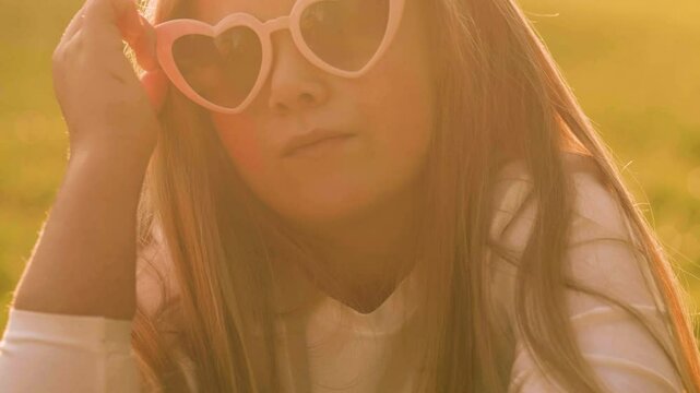 Summer portrait of a cute little girl in a heart sunglasses. Happy childhood concept.