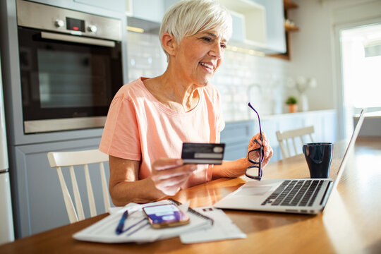 Senior woman shopping online with credit card and laptop at home