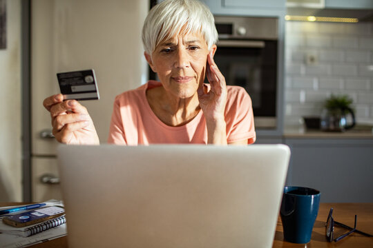 Senior woman shopping online with credit card and laptop at home