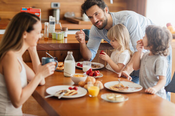 Young family enjoying breakfast together in the kitchen