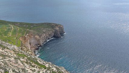 Panoramic view of towering coastal cliffs merging with lush greenery, overlooking the blue sea with...