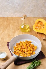 Preparing the filling for pumpkin ravioli or salad, fried pumpkin pieces in a light frying pan.